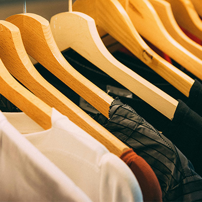 Minimalist photo of assorted garments on hangers, linking to the full apparel collection and shop homepage.