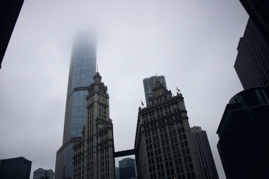 A dramatic upward view of Chicago’s iconic clock tower vanishing into low-hanging December clouds. The looming skyscraper appears to fade into the mist, evoking a surreal, dreamlike cityscape.