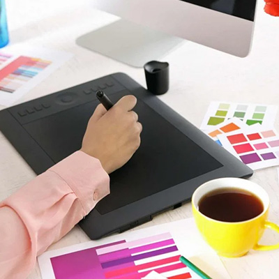 Woman’s hand using a digital drawing tablet beside a coffee cup, symbolizing digital art tools and creative workflow.